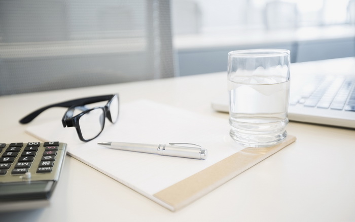 Image of desk with pen, pad and glasses